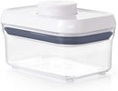 A small, rectangular, clear plastic food storage container with a white push-button lid and a blue silicone airtight seal.
