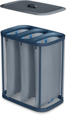 A dark blue Joseph Joseph Tota Trio laundry hamper with three separate internal compartments, each with a handle. The gray lid is propped against the side of the hamper.