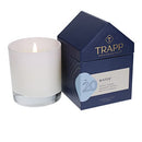 The Trapp No. 20 Water House Box Candle burning, creating a warm ambiance next to its elegant house-shaped packaging.