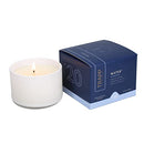 The Trapp No. 20 Water Small Poured Candle burning, creating a warm ambiance next to its elegant packaging.