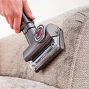 Close-up of pet hair being vacuumed from a couch with a mini tool.
