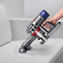 Dyson V8 handheld mode cleaning pet hair off a white couch with motorized tool.