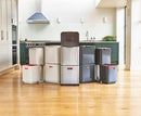 A two-tiered stainless steel trash and recycling bin with a black lid and base. The top compartment has a small, horizontal orange light on its front.