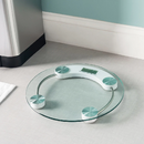 Clear round glass bathroom scale with chrome frame and digital LCD screen.