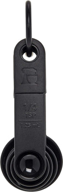 Five Black KitchenAid measuring spoon set including 1 tbsp, 1 tsp, 1/2 tsp, 1/4 tsp, and 1/8 tsp sizes.