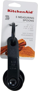 Five Black KitchenAid measuring spoon set including 1 tbsp, 1 tsp, 1/2 tsp, 1/4 tsp, and 1/8 tsp sizes.
