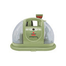 A green BISSELL Little Green portable carpet and upholstery cleaner with its hose and cleaning tool visible.