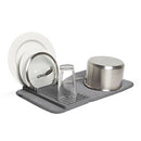 A compact, gray drying rack designed for dishes and cookware. It features a removable, ribbed silicone mat for drainage.