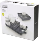 box of Joseph Joseph gray expandable dish drying rack with cutlery holder and drainboard set on a white background.