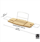A light wood Umbra bathtub caddy with expandable metal arms, featuring a slotted book/tablet stand, a wine glass holder, and a recessed area with drain holes for soap or accessories.
