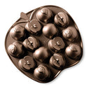 A brown/bronze heavy cast aluminum baking pan shaped like an apple. It has 14 cavities for baking small apple-shaped cakelets, some whole and some halved.