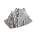 Nordic Ware silver gingerbread house Bundt pan with detailed holiday-themed mold on a white background.