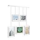 A contemporary white photo display featuring five square frames suspended from a horizontal bar by thin rods.
