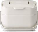 A ventilated, rectangular Joseph Joseph compost bin with the lid open, showing the built-in odor filter and a compostable liner inside.