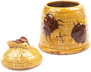 A whimsical ceramic honey pot designed like a yellow beehive with textured walls, featuring two dark brown bees on its exterior and a fitted lid with a small bee on top.