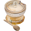 A golden-hued crystal honey dish with a faceted, geometric design and a matching lid. A wooden honey dipper rests in front of the dish.