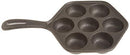 The image displays a cast iron aebleskiver pan. It's a dark-colored pan with a single handle and seven hemispherical indentations, which are used to cook aebleskiver (Danish pancake balls). The shape of the pan, excluding the handle, is hexagonal.