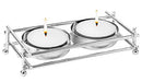 A boxed set featuring a shiny, rectangular, nickel-plated metal frame holder designed for two mini tealight candles, with two white tealights included.