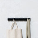 Black Umbra Flip 5 Hook wall-mounted coat rack with retractable hooks on a white background.