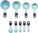 A set of nine light blue KitchenAid measuring cups and spoons with black soft-grip handles, spread out on a white surface. The set includes four cups and five spoons.