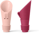 A set of two Houdini Flipper bottle stoppers, one in pink and one in red. They have a ribbed rubber base to fit into bottles and a flip-top spout for pouring and sealing.