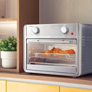 A Silver Brentwood 1700-Watt 24 Quart Convection Air Fryer Toaster Oven that has  glass door revealing the interior. The front of the oven features two control knobs, for temperature and timer selection, and a power indicator light. 