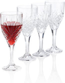 A set of four elegant crystal cut glass wine goblets with a diamond-cut pattern. One goblet is filled with red wine, while the others are empty, showcasing the intricate design and stem.