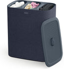 A dark blue Joseph Joseph Tota Trio laundry hamper with three separate internal compartments, each with a handle. The gray lid is propped against the side of the hamper.