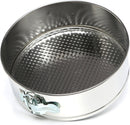 A round, metallic springform pan with a textured, fluted base and a quick-release latch on the side.