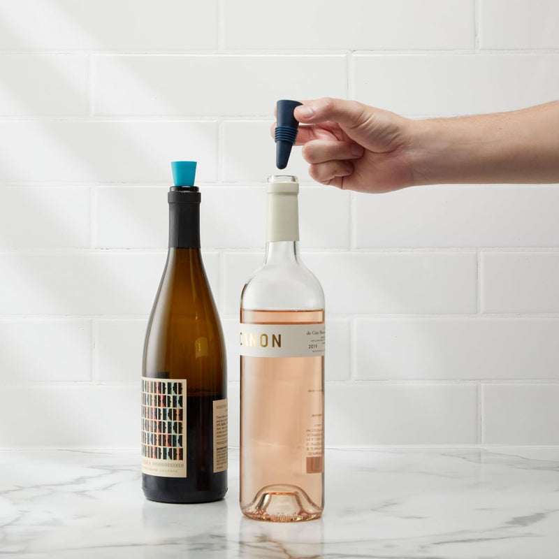 Two sets of packaged Houdini silicone wine stoppers. One package contains navy blue and bright blue stoppers, and the other contains burgundy and light pink stoppers.