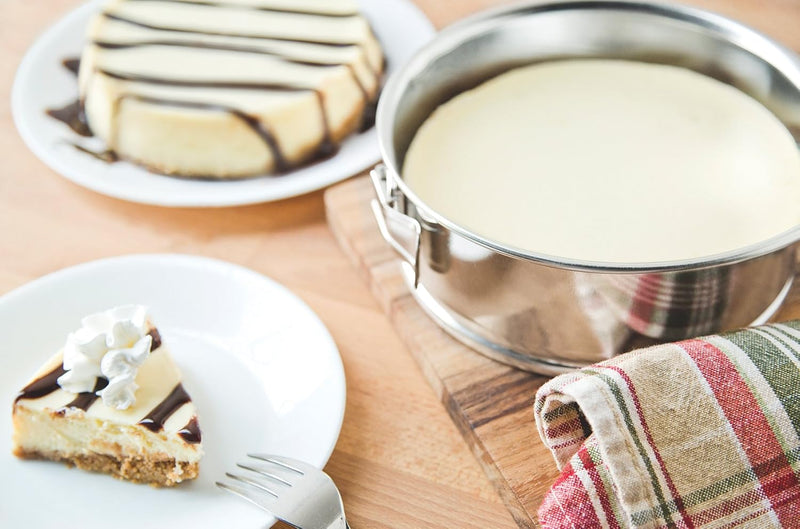 A round, metallic springform pan with a textured, fluted base and a quick-release latch on the side.