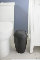 Black trash can positioned between toilet and vanity