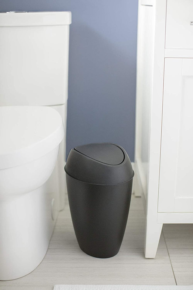 Black trash can positioned between toilet and vanity