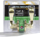 A pair of polished brass door knobs in clear plastic packaging. The knobs have a curved lever design and are for an interior non-locking passage door.