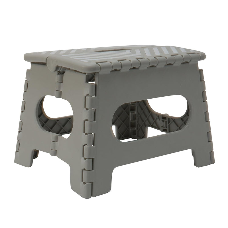 A grey plastic foldable step stool with a carrying handle. The top has an anti-slip pattern, and the stool is shown in its open, ready-to-use position.