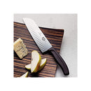 The Victorinox Santoku knife resting on a dark wooden serving board with sliced cheese and fruit.
