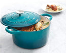 Dutch oven filled with cooked chicken and vegetables on white background