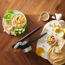 Black potato and vegetable ricer with a sturdy design, showing a metal mashing basket and long handles.