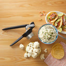 Chef’n ricer next to a bowl of cauliflower rice and tacos on a wooden surface.