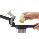 Hand placing a peeled potato into the ricer’s stainless steel basket.
