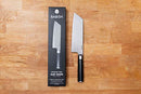 Babish Clef knife standing upright on wooden cutting board with retail packaging