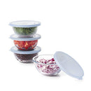 The OXO Good Grips 8-Piece Glass Prep Bowl Set is displayed with four glass bowls stacked, each containing chopped cilantro, tomatoes, black beans, and diced red onion, respectively, and sealed with a light blue silicone lid. A fifth open glass bowl with diced red onion and a separate lid are shown in the foreground.