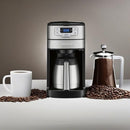 Front view of Cuisinart coffee grinder and brewer placed on a counter with a mug, French press, and coffee beans.