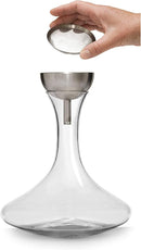 A glass wine decanter with a wide base and narrow neck, shown with a stainless steel "wine shower" funnel and a detached fine-mesh sediment strainer.