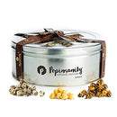 A round, silver metal gift tin with a clear lid divided into three sections, containing three different flavors of gourmet popcorn and tied with a brown ribbon.