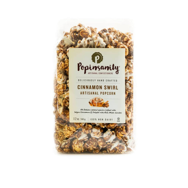 A bag of Popinsanity Cinnamon Swirl Artisanal Popcorn, featuring caramel-coated popcorn infused with cinnamon and drizzled with white chocolate, elegantly packaged for gifting and gourmet snacking.