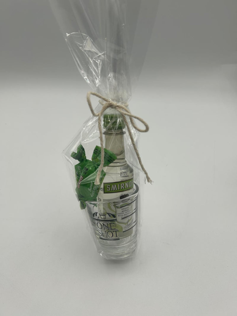 The Twisted Apple gift set wrapped in clear cellophane and tied with rustic twine, displaying the vodka bottle, shot glass, and candies inside.