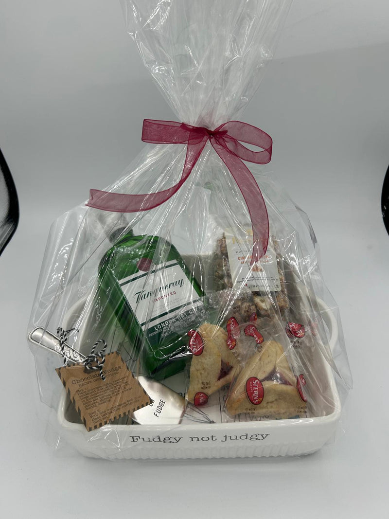 The fully wrapped Shalach Manos gift set, elegantly presented in clear cellophane and tied with a red ribbon. Inside, the white ceramic baking dish with an illustrated fudge recipe is accompanied by a bottle of Tanqueray London Dry Gin, a bag of Popinsanity Cinnamon Swirl Popcorn, and two Stern’s Hamantaschen cookies, creating a festive and indulgent Purim gift.