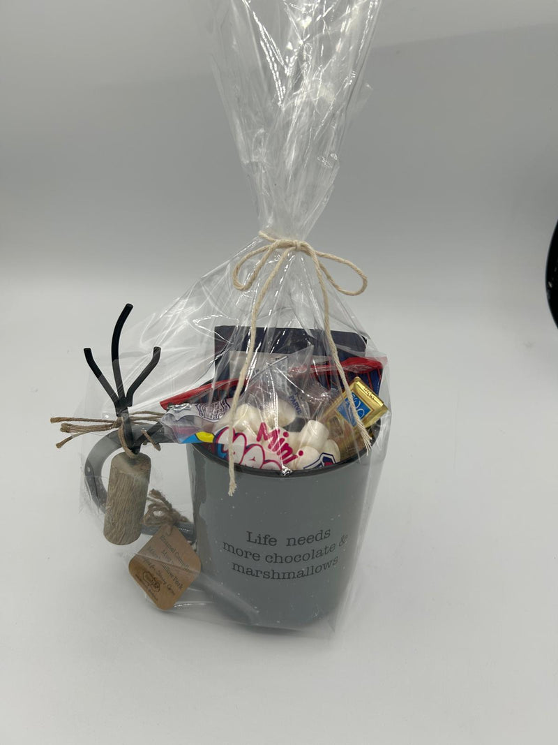 The fully wrapped Shalach Manos hot chocolate gift set, elegantly presented in clear cellophane and tied with twine. Inside, the dark gray enamel mug is filled with Ko-Sure Instant Hot Cocoa Mix, mini marshmallows, pretzels, and Alprose chocolates, creating a warm and festive Purim gift.