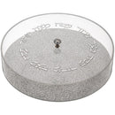 A modern acrylic round Matzah box with a glitter-textured base and a clear acrylic cover, featuring elegant Hebrew lettering around the lid. A small crystal-like handle adds a stylish touch.
